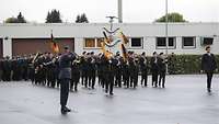 Viele Menschen marschieren in schwarzen Uniformen. Alle spielen ein Instrument.