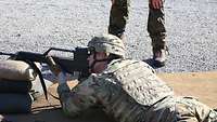Soldat liegt auf dem Boden und hat das Gewehr im Anschlag.