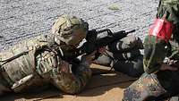 Soldat liegt auf dem Boden mit dem Gewehr im Anschlag.