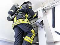 Feuerwehrmann Endlosleiter Atemschutzstrecke Feuerwehrmann in voller Ausrüstung steht auf einer metallenen Leiter.