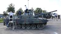 Die Schüler stehen auf einem Panzer. Ein Soldat beantwortet ihre Fragen. Im Hintergrund stehen weitere Bundeswehrfahrzeuge.