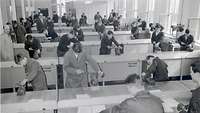 Monochrome picture of many men working in a hall