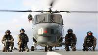 Hubschrauberteam Vier Soldaten, zwei links, zwei rechts knien mit den abgenommenen Laschen neben dem Sea Lynx