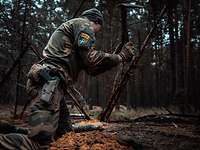 Ein Soldat kniet auf dem Waldboden und bereitet ein Baumhindernis vor 