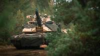 Ein US-Amerikanischer Kampfpanzer Abrams fährt mit hoher Geschwindigkeit durch den Wald