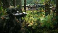 Ein Kampfpanzer Leopard weicht aus. Im Vordergrund befindet sich ein Soldat mit einer Panzerfaust.