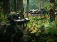 Ein Kampfpanzer Leopard weicht aus. Im Vordergrund befindet sich ein Soldat mit einer Panzerfaust.
