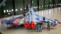 Ein Eurofighter steht im Hangar und wird mit einer Sonderfolierung beklebt