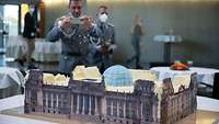 Ein Soldat fotografiert das Reichstagsgebäude, das als Kuchen auf einem Tisch steht