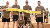 Vier Soldaten und eine Soldatin halten ein gelbes Band, auf dem „Kameradschaftslauf Gao“ steht. 