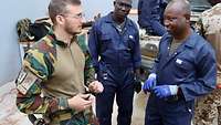 Malische Männer stehen zusammen mit einem belgischen Soldaten und unterhalten sich