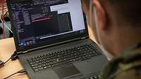 Ein Soldat blickt auf seinen Laptop.