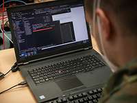 Ein Soldat blickt auf seinen Laptop.