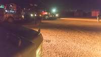 Unterschiedliche geschützte Fahrzeuge stehen aufgereiht nebeneinander auf einer Sandfläche 