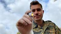 Ein Mann hat eine Pupillenlampe in der Hand und leuchtet in die Kamera