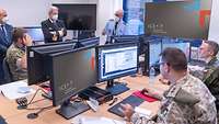 Soldaten arbeiten an ihren Computern und einige stehen dahinter.
