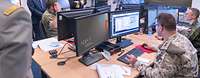 Soldaten arbeiten an ihren Computern und einige stehen dahinter.