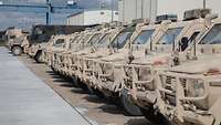 Eine lange Reihe Bundeswehr-Fahrzeuge steht auf einem Hof.
