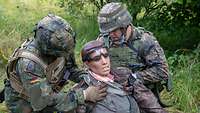 Zwei Soldaten kümmern sich im Freien um eine verletzte Simulationspuppe