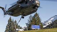 Drei Soldaten arbeiten unter der knapp über ihnen fliegenden CH-53.