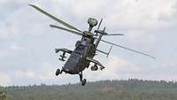 Ein Hubschrauber fliegt über einem Wald.