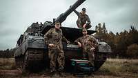 Drei Soldaten stehen an einer Panzerhaubitze 2000