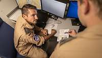 Ein Soldat übergibt einen anderen Soldaten Informationen.