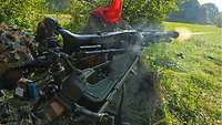 Ein Soldat schießt mit einem lafettierten Maschinengewehr aus seiner liegenden Stellung.