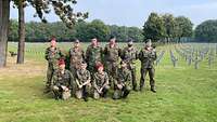 Gruppenfoto der zehn Soldaten, die auf dem Friedhof unterstützten. Im Hintergrund ist der Friedhof zu sehen.