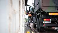 Ein Soldat steigt aus seinem Fahrzeug, dass auf einem Waggon steht, aus.