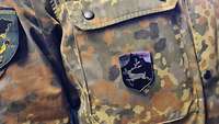 Ein Abzeichen mit einem Hirsch an der Brusttasche einer Flecktarn-Uniform