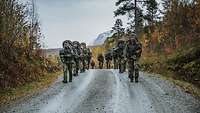 Soldaten marschieren mit Gepäck durch ein bergiges Gelände