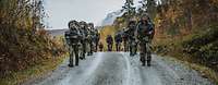 Joint Mountain Training Soldaten marschieren mit Gepäck durch ein bergiges Gelände