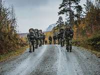 Joint Mountain Training Soldaten marschieren mit Gepäck durch ein bergiges Gelände