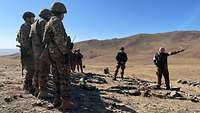 Mehrere Soldaten folgen in kahlem, gebirgigem Gelände den Ausführungen eines Soldaten, der vor ihnen steht.