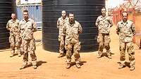 Sechs Soldaten vor zwei großen schwarzen Zisternen. Im Hintergrund steht ein Lkw.