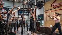 Mehrere Personen in einem Fitnessstudio beim Gewichtheben