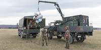 Soldaten verladen eine Drohne KZO mit einem Kran auf der Pritsche eines Lkw 2t gl Unimog