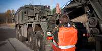 Ein Soldat mit Warnweste weist den Kraftfahrer eines Schwerlasttransporters Mammut mittels Handzeichen beim Ankuppeln ein.