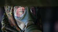Ein Soldat mit hochrotem Kopf trägt eine ABC-Schutz-Maske.