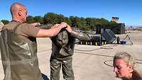 Erschöpfte deutsche ABC-Soldaten helfen sich gegenseitig beim Ausziehen ihrer ABC-Schutzausstattung.