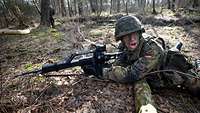 Dienstpostenausbildung Jäger Ein Soldat liegt mit Waffe im Gelände und ruft etwas