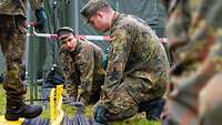 Mehrere Soldaten verlegen Energieleitungen.