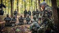 Soldaten hocken auf dem Waldboden um eine Lagekarte aus Steinen, Blättern und Stöcken.