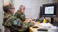 Zwei Soldaten sitzen nebeneinander an einem Tisch und schauen auf die Bildschirme ihrer PCs