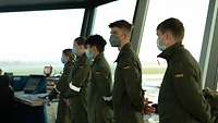 Fünf Schüler gekleidet in Fliegerkombis stehen in einem Tower.