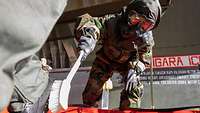 Schuh-Dekontamination Ein Soldat in Schutzausrüstung bürstet den Stiefel eines Piloten ab.