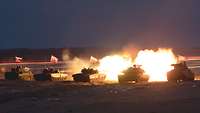 Bei Nacht schießen drei Panzer gleichzeitig. Große Feuerbälle schießen aus Panzerrohren heraus.