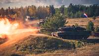 Ein deutscher Panzer Leopard 2 mit niederländischer Besatzung schießt. Aus dem Panzerrohr tritt ein Feuerball heraus. 