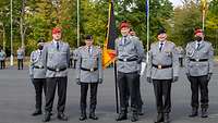 Mehrere Soldaten stehen nebeneinander, zwischen ihnen die Truppenfahne.